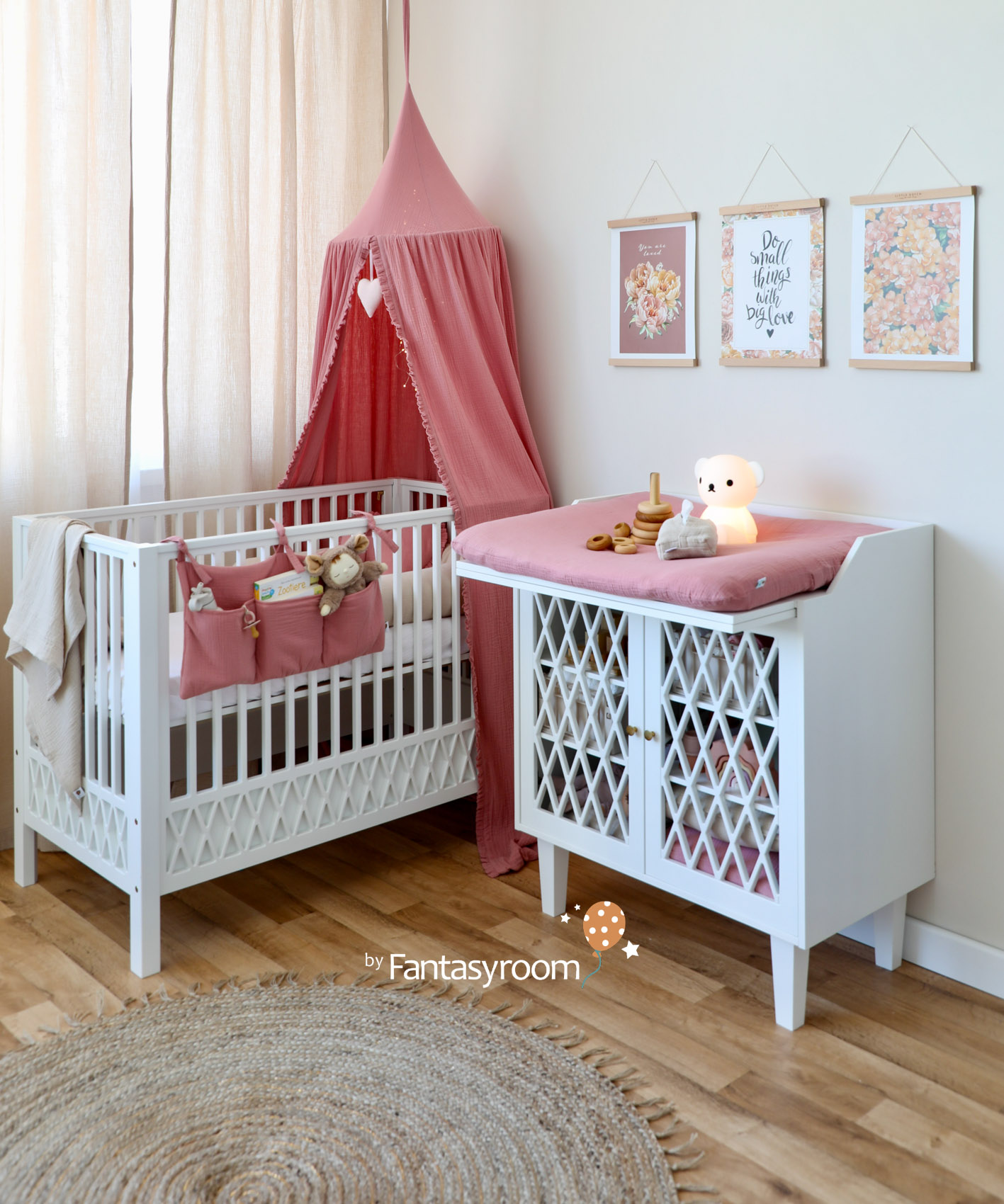 Babyzimmer mit weißen Möbeln, cremefarbenen Wänden und altrosa Textilien